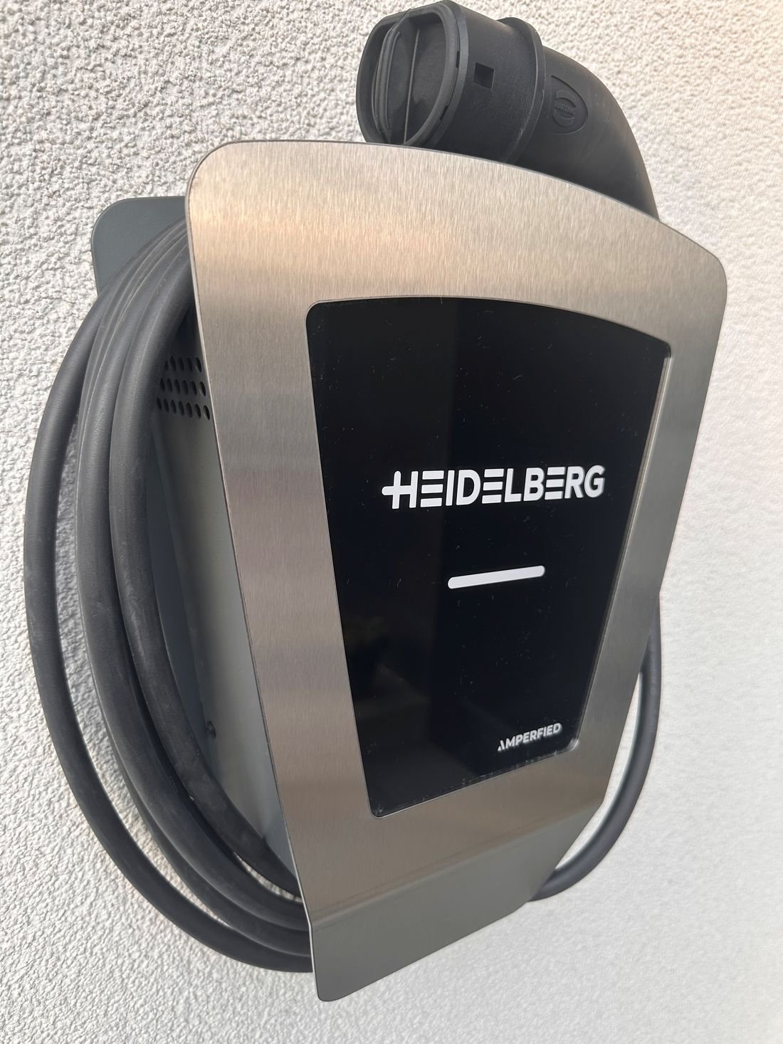 Wallbox mit aufgewickeltem Ladekabel an einer Hauswand